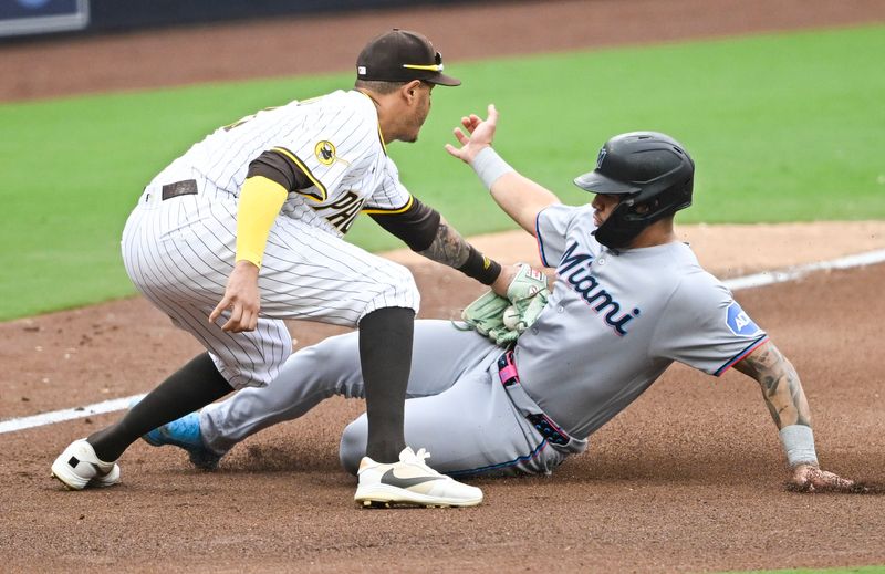 May 28, 2025; San Diego, California, USA; Miami Marlins catcher Agustin Ramirez (50) is tagged out at third base by San Diego Padres third baseman Manny Machado (13) during the seventh inning at Petco Park.  Mandatory Credit: Denis Poroy-Imagn Images