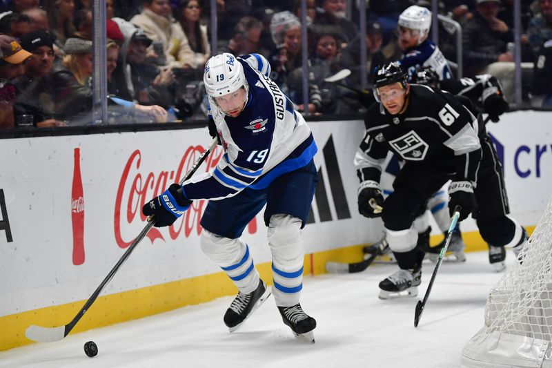 Dec 13, 2023; Los Angeles, California, USA; Winnipeg Jets center David Gustafsson (19) moves the puck aheado fLos Angeles Kings center Trevor Lewis (61) during the third period at Crypto.com Arena. Mandatory Credit: Gary A. Vasquez-USA TODAY Sports