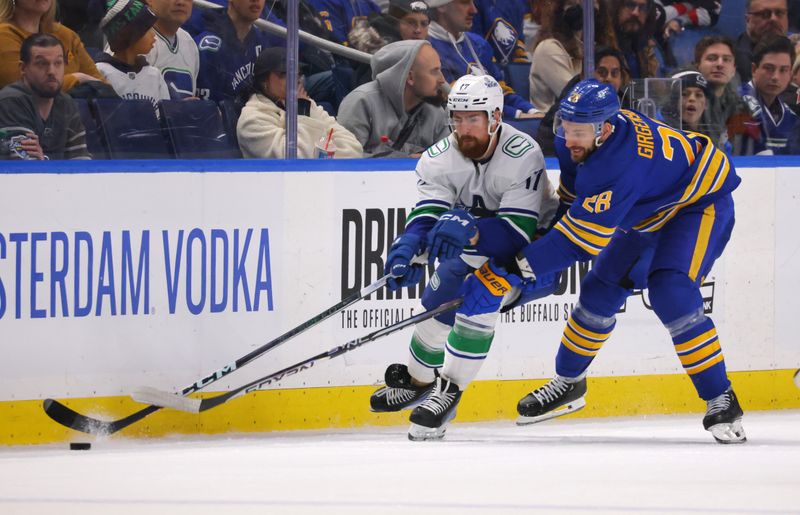 Jan 13, 2024; Buffalo, New York, USA;  Vancouver Canucks defenseman Filip Hronek (17) and Buffalo Sabres left wing Zemgus Girgensons (28) go after a loose puck during the third period at KeyBank Center. Mandatory Credit: Timothy T. Ludwig-USA TODAY Sports