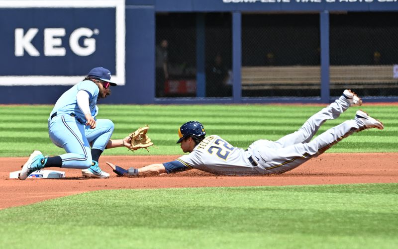 Jun 1, 2023; Toronto, Ontario, CAN;  Milwaukee Brewers designated hitter Christian Yelich (22) is tagged out by Toronto Blue Jays shortstop Bo Bichette (11) trying to steal second base in the first inning at Rogers Centre. Mandatory Credit: Dan Hamilton-USA TODAY Sports