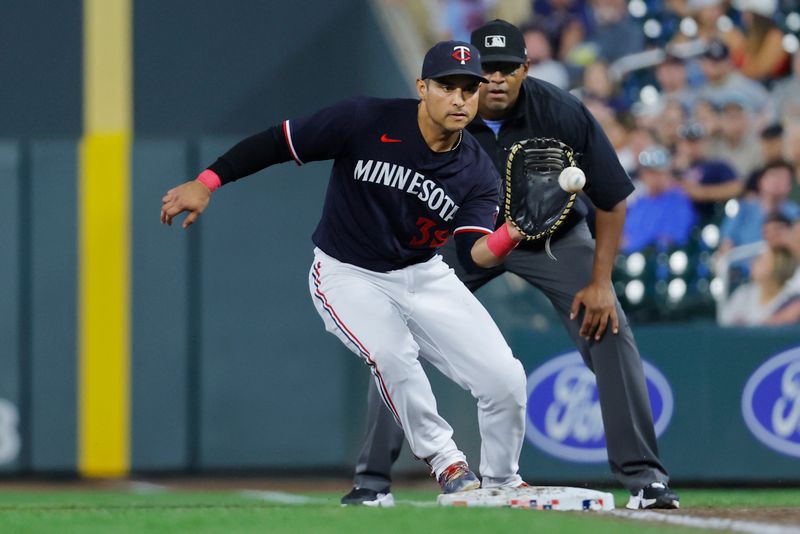 Aug 29, 2023; Minneapolis, Minnesota, USA; Minnesota Twins first baseman Donovan Solano (39) fields a ball over first as umpire Jose Navas watches in the ninth inning at Target Field. Mandatory Credit: Bruce Kluckhohn-USA TODAY Sports