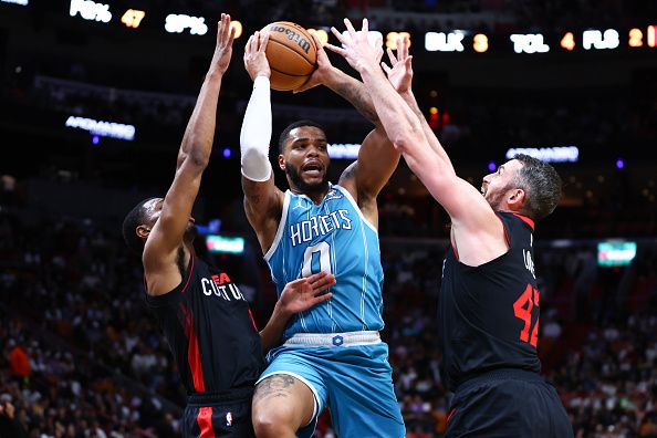 MIAMI, FLORIDA - DECEMBER 13: Miles Bridges #0 of the Charlotte Hornets drives against Jamal Cain #8 and Kevin Love #42 of the Miami Heat during the third quarter of the game at Kaseya Center on December 13, 2023 in Miami, Florida. NOTE TO USER: User expressly acknowledges and agrees that, by downloading and or using this photograph, User is consenting to the terms and conditions of the Getty Images License Agreement. (Photo by Megan Briggs/Getty Images)