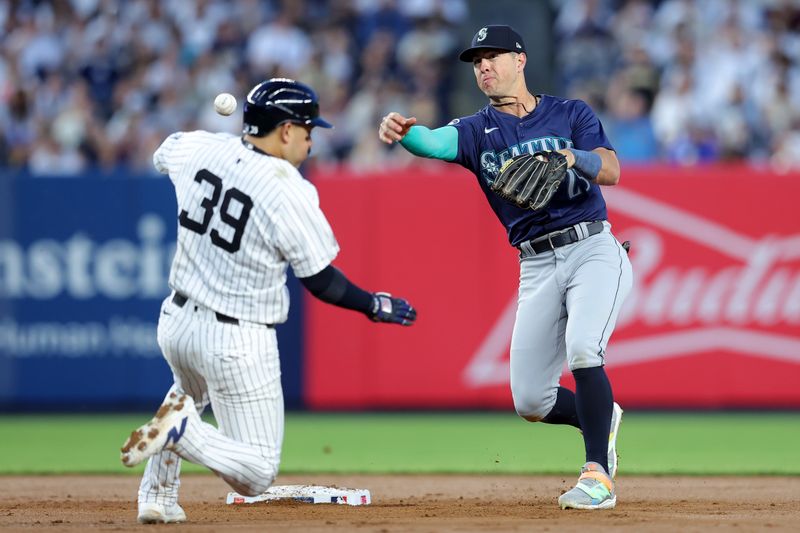 May 20, 2024; Bronx, New York, USA; Seattle Mariners shortstop Dylan Moore (25) forces out New York Yankees catcher Jose Trevino (39) at second base then throws to first to complete a double play on a ball hit by Yankees third baseman Jon Berti (not pictured) during the fourth inning at Yankee Stadium. Mandatory Credit: Brad Penner-USA TODAY Sports