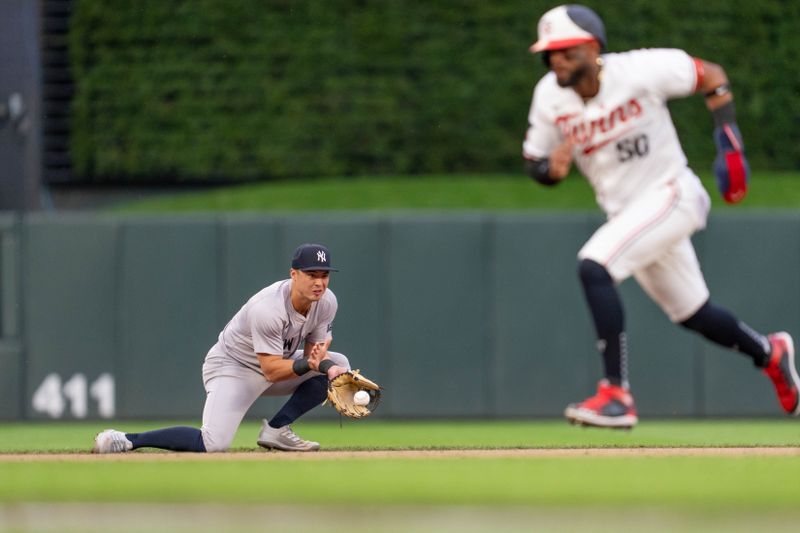 May 15, 2024; Minneapolis, Minnesota, USA; New York Yankees shortstop Anthony Volpe (11) fields a hit by Minnesota Twins third base Jose Miranda (64) as Minnesota Twins center fielder Willi Castro (50) runs to third base in the second inning at Target Field. Mandatory Credit: Matt Blewett-USA TODAY Sports