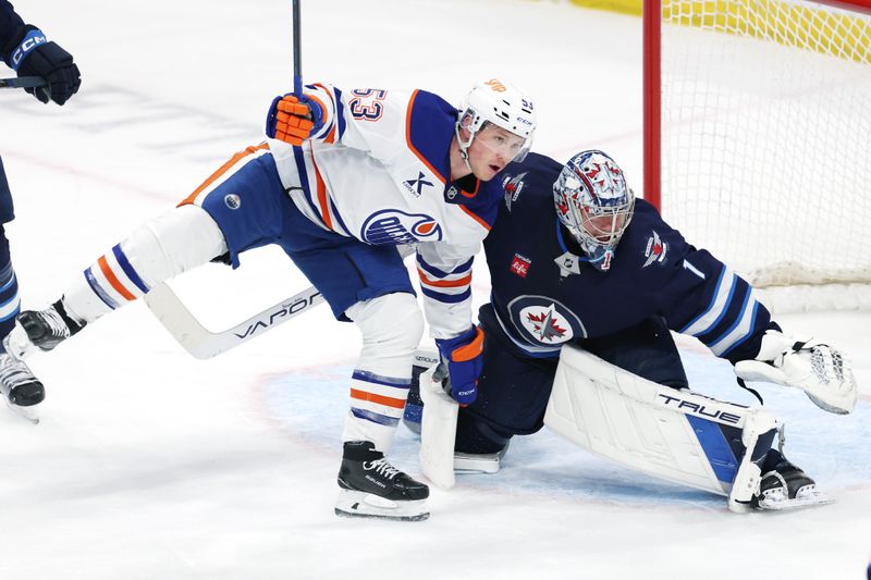 Apr 13, 2025; Winnipeg, Manitoba, CAN; Edmonton Oilers center Jeff Skinner (53) collides with Winnipeg Jets goaltender Eric Comrie (1) in the third period at Canada Life Centre. Mandatory Credit: James Carey Lauder-Imagn Images