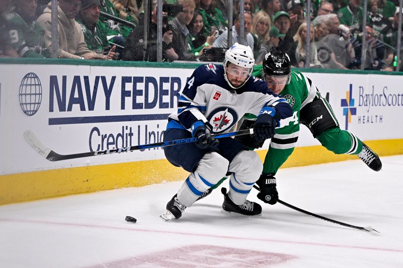 May 11, 2025; Dallas, Texas, USA; Winnipeg Jets defenseman Neal Pionk (4) and d24 battles for control of the puck during the second period in game three of the second round of the 2025 Stanley Cup Playoffs at American Airlines Center. Mandatory Credit: Jerome Miron-Imagn Images