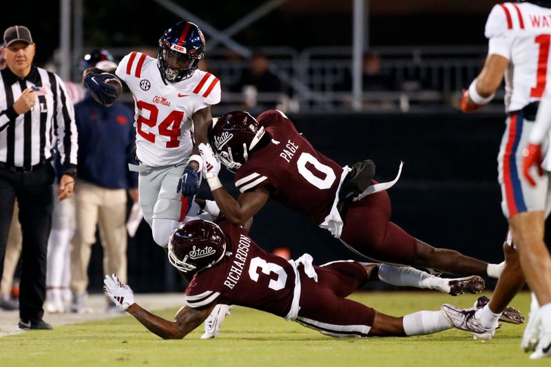 Nov 23, 2023; Starkville, Mississippi, USA; Mississippi Rebels running back Ulysses Bentley IV (24) runs the ball  as Mississippi State Bulldogs defensive back Decamerion Richardson (3) and Mississippi State Bulldogs linebacker DeShawn Page (0) make the tackle during the first half at Davis Wade Stadium at Scott Field. Mandatory Credit: Petre Thomas-USA TODAY Sports