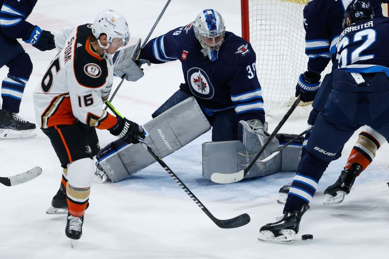 Mar 15, 2024; Winnipeg, Manitoba, CAN; Winnipeg Jets goalie Laurent Boissoit (39) and Anaheim Ducks forward Ryan Strome (16) eye the puck during the third period at Canada Life Centre. Mandatory Credit: Terrence Lee-USA TODAY Sports