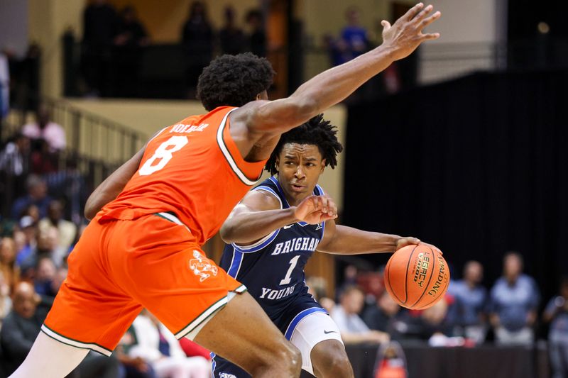 Nov 27, 2025; Kissimmee, Florida, USA; Brigham Young University Cougars guard Robert Wright III (1) drives tot he basket past Miami (FL) Hurricanes center Ernest Udeh Jr. (8) in the second half at State Farm Field House. Mandatory Credit: Nathan Ray Seebeck-Imagn Images