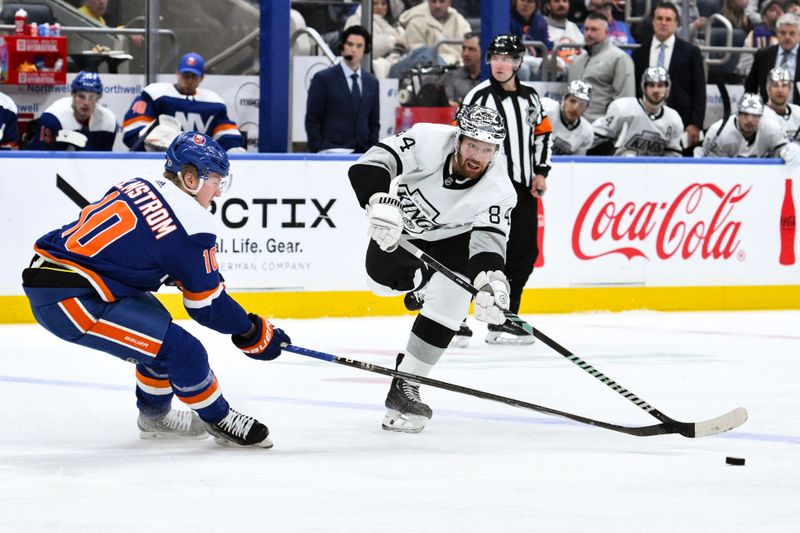 Dec 9, 2023; Elmont, New York, USA; Los Angeles Kings defenseman Vladislav Gavrikov (84) passes the puck while being defended by New York Islanders right wing Simon Holmstrom (10) during the first period at UBS Arena. Mandatory Credit: John Jones-USA TODAY Sports