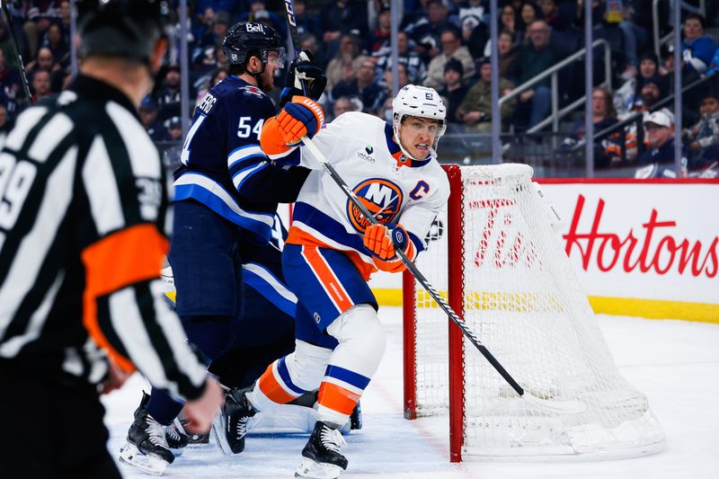 Jan 13, 2026; Winnipeg, Manitoba, CAN; New York Islanders forward Anders Lee (27) tries to skate away from Winnipeg Jets defenseman Dylan Samberg (54) during the first period at Canada Life Centre. Mandatory Credit: Terrence Lee-Imagn Images