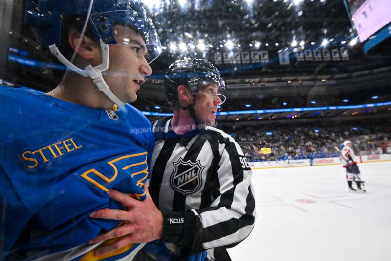 Mar 24, 2026; St. Louis, Missouri, USA; St. Louis Blues right wing Jimmy Snuggerud (21) is held back by linesman David Brisebois (96) after he got in a scrum with Washington Capitals right wing Tom Wilson (not pictured) during the second period at Enterprise Center. Mandatory Credit: Jeff Curry-Imagn Images