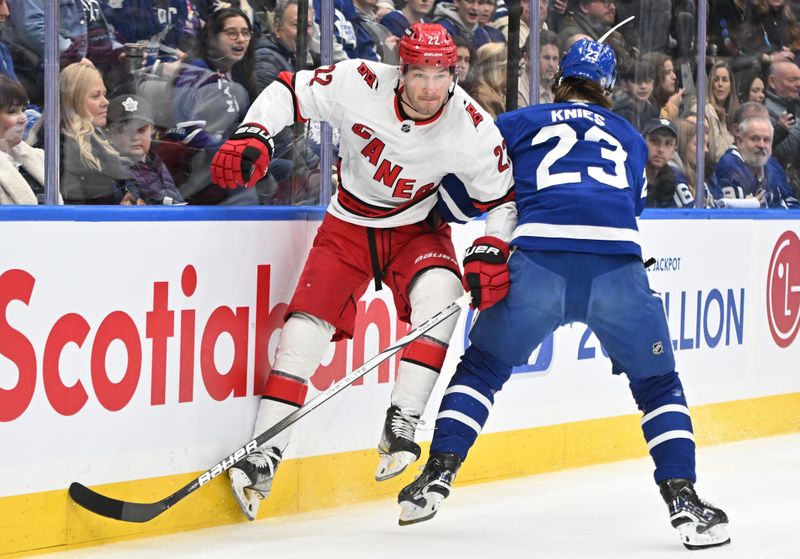 Dec 30, 2023; Toronto, Ontario, CAN; Toronto Maple Leafs forward Matthew Knies (23) body checks Carolina Hurricanes defenseman Brett Pesce (22) in the first period at Scotiabank Arena. Mandatory Credit: Dan Hamilton-USA TODAY Sports