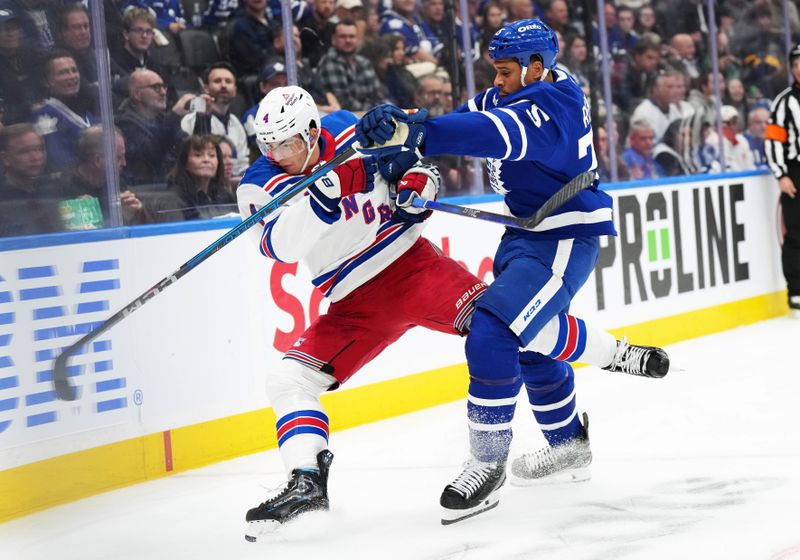 Oct 19, 2024; Toronto, Ontario, CAN; Toronto Maple Leafs right wing Ryan Reaves (75) battles for the puck with New York Rangers defenseman Braden Schneider (4) during the first period at Scotiabank Arena. Mandatory Credit: Nick Turchiaro-Imagn Images