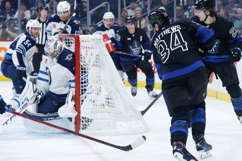 Oct 28, 2024; Winnipeg, Manitoba, CAN; Winnipeg Jets goalie Connor Hellebuyck (37) makes a save on a shot by Toronto Maple Leafs forward Auston Matthews (34) during the first period at Canada Life Centre. Mandatory Credit: Terrence Lee-Imagn Images