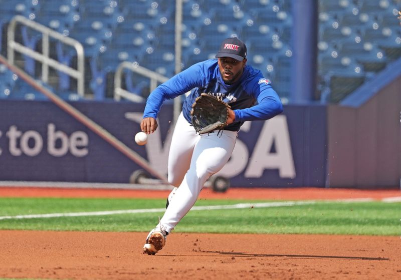 Sep 11, 2024; Toronto, Ontario, CAN; Toronto Blue Jays third base Luis De Los Santos (20) fields a ball during batting practice wearing a City of New York Fire Department baseball cap before a game against the New York Mets at Rogers Centre. Mandatory Credit: Nick Turchiaro-Imagn Images