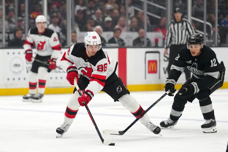 Nov 1, 2025; Los Angeles, California, USA; New Jersey Devils center Jack Hughes (86) and Los Angeles Kings left wing Trevor Moore (12) reach for the puck in the first period at Crypto.com Arena. Mandatory Credit: Kirby Lee-Imagn Images