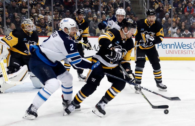 Jan 13, 2023; Pittsburgh, Pennsylvania, USA;  Pittsburgh Penguins left wing Jake Guentzel (59) clears the puck against pressure from Winnipeg Jets defenseman Dylan DeMelo (2) during the first period at PPG Paints Arena. Mandatory Credit: Charles LeClaire-USA TODAY Sports