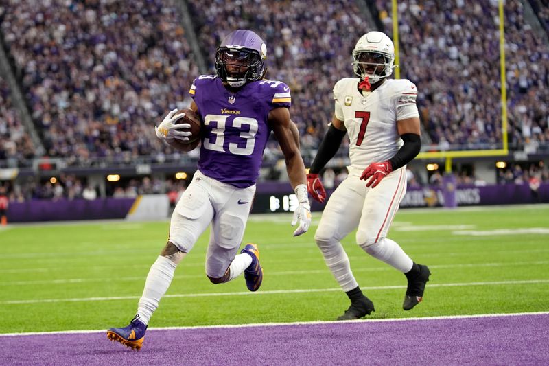 Minnesota Vikings running back Aaron Jones (33) catches a 5-yard touchdown pass in front of Arizona Cardinals linebacker Kyzir White (7) during the second half of an NFL football game Sunday, Dec. 1, 2024, in Minneapolis. (AP Photo/Abbie Parr)