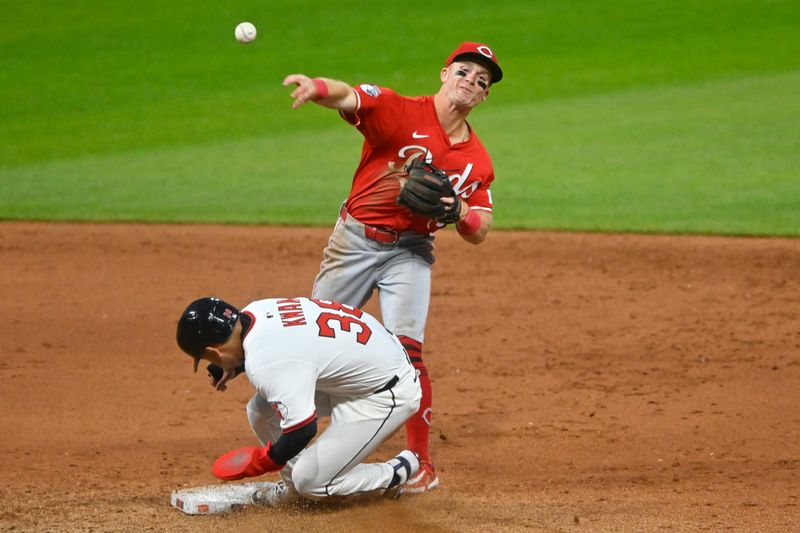 Jun 10, 2025; Cleveland, Ohio, USA; Cincinnati Reds second baseman Matt McLain (9) turns a double play beside Cleveland Guardians left fielder Steven Kwan (38) in the ninth inning at Progressive Field. Mandatory Credit: David Richard-Imagn Images