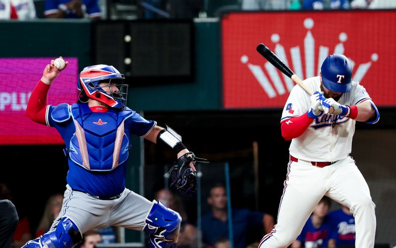 May 27, 2025; Arlington, Texas, USA; Toronto Blue Jays catcher Alejandro Kirk (30) makes a wild throw to third base as Texas Rangers first baseman Jake Burger (21) ducks during the eighth inning at Globe Life Field. Mandatory Credit: Kevin Jairaj-Imagn Images