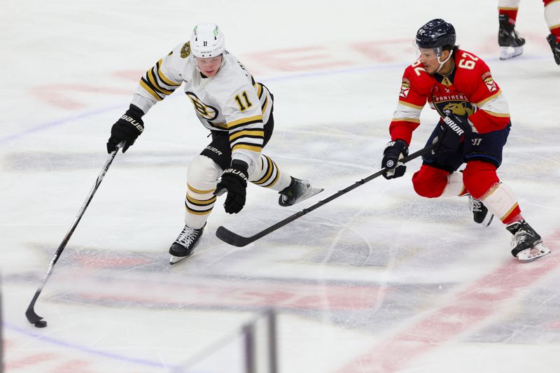 Nov 22, 2023; Sunrise, Florida, USA; Boston Bruins center Trent Frederic (11) protects the puck from Florida Panthers defenseman Brandon Montour (62) during the third period at Amerant Bank Arena. Mandatory Credit: Sam Navarro-USA TODAY Sports