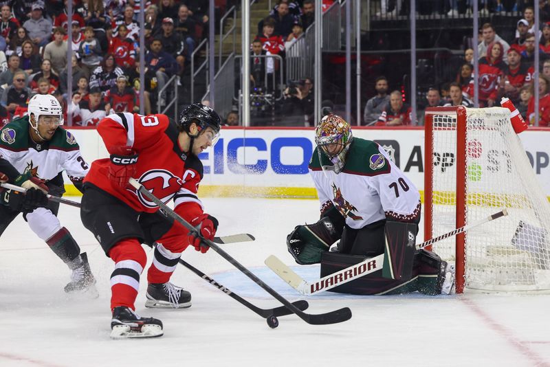 Oct 13, 2023; Newark, New Jersey, USA; Arizona Coyotes goaltender Karel Vejmelka (70) defends his net against New Jersey Devils center Nico Hischier (13) during the second period at Prudential Center. Mandatory Credit: Ed Mulholland-USA TODAY Sports