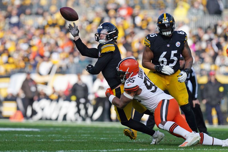 FILE - Pittsburgh Steelers quarterback Kenny Pickett, top left, gets off a pass while in the grasp of Cleveland Browns defensive end Myles Garrett (95) during the first half of an NFL football game in Pittsburgh, Sunday, Jan. 8, 2023. Garrett has five straight seasons with double-digit sacks and is third in the NFL in total sacks with 74 1/2 since entering the league as the top pick in 2017. (AP Photo/Matt Freed, File)