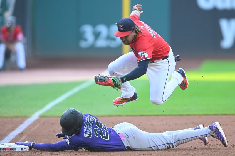 Jul 29, 2025; Cleveland, Ohio, USA; Cleveland Guardians third baseman Jose Ramirez (11) leaps over Colorado Rockies first baseman Warming Bernabel (25) after tagging him out attempting to steal third base in the second inning at Progressive Field. Mandatory Credit: David Richard-Imagn Images