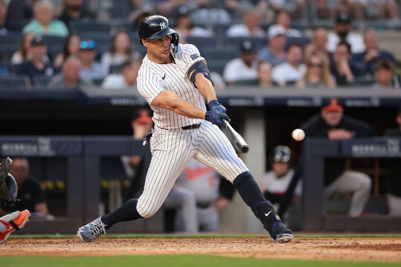 Jun 18, 2024; Bronx, New York, USA; New York Yankees designated hitter Giancarlo Stanton (27) hits an RBI single during the third inning against the Baltimore Orioles at Yankee Stadium. Mandatory Credit: Vincent Carchietta-USA TODAY Sports