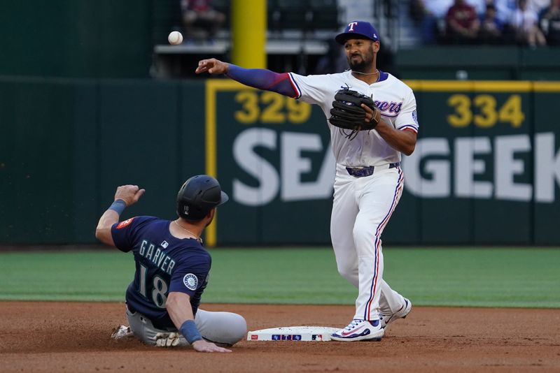 May 3, 2025; Arlington, Texas, USA; Texas Rangers second baseman Marcus Semien (2) turns the double play on Seattle Mariners catcher Mitch Garver (18) during the first inning at Globe Life Field. Mandatory Credit: Raymond Carlin III-Imagn Images