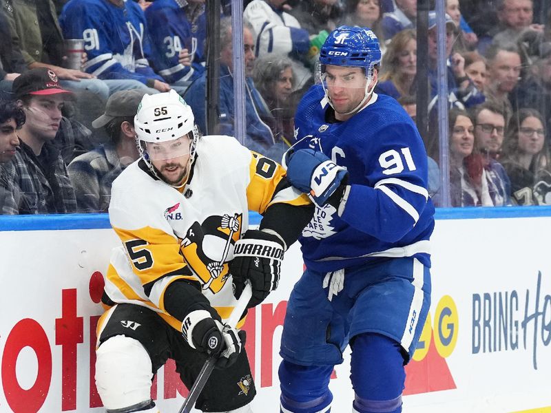 Apr 8, 2024; Toronto, Ontario, CAN; Toronto Maple Leafs center John Tavares (91) battles for the puck with Pittsburgh Penguins defenseman Erik Karlsson (65) during the third period at Scotiabank Arena. Mandatory Credit: Nick Turchiaro-USA TODAY Sports