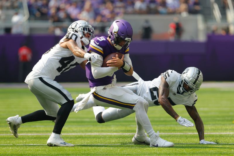 Minnesota Vikings quarterback J.J. McCarthy (9) is hit by Las Vegas Raiders safety Jaydon Grant (40) as he scramble for yards during the first half of an NFL football game Saturday, Aug. 10, 2024, in Minneapolis. (AP Photo/Bruce Kluckhohn)