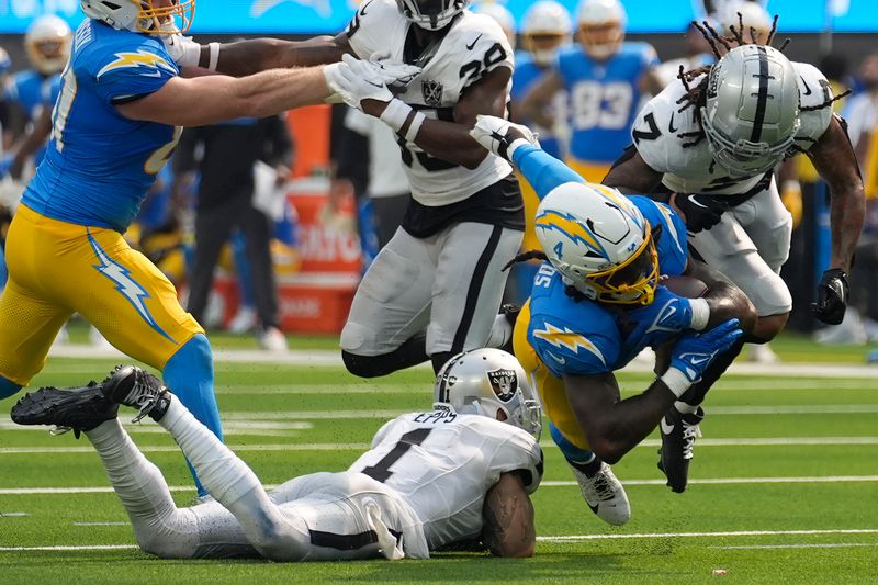 Los Angeles Chargers running back Gus Edwards, middle right, falls forward in front of Las Vegas Raiders safety Marcus Epps (1) and safety Tre'von Moehrig (7) during the second half of an NFL football game, Sunday, Sept. 8, 2024, in Inglewood, Calif. (AP Photo/Marcio Jose Sanchez)