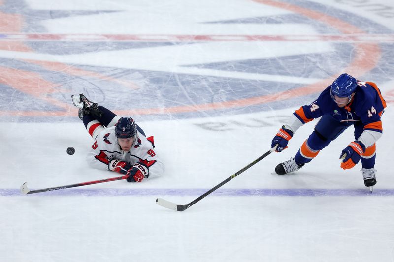 Oct 11, 2025; Elmont, New York, USA; Washington Capitals right wing Ryan Leonard (9) fights for the puck against New York Islanders center Bo Horvat (14) during the first period at UBS Arena. Mandatory Credit: Brad Penner-Imagn Images