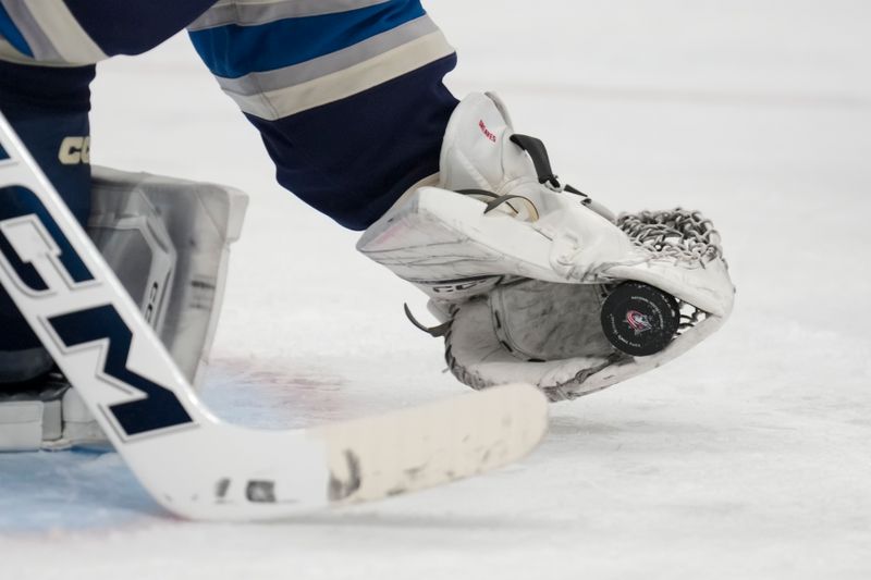 Apr 4, 2024; Columbus, Ohio, USA;  The Columbus team logo is seen on the game puck as Columbus Blue Jackets goaltender Jet Greaves (73) makes a save in net against the New York Islanders in the third period at Nationwide Arena. Mandatory Credit: Aaron Doster-USA TODAY Sports