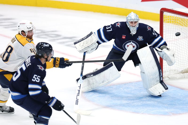 Oct 18, 2025; Winnipeg, Manitoba, CAN; Nashville Predators defenseman Nick Perbix (48) tries to bat down the puck in front of Winnipeg Jets goaltender Connor Hellebuyck (37) in the third period at Canada Life Centre. Mandatory Credit: James Carey Lauder-Imagn Images