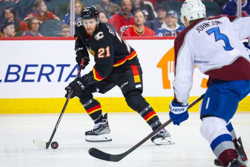 Mar 12, 2024; Calgary, Alberta, CAN; Calgary Flames center Kevin Rooney (21) controls the puck against Colorado Avalanche defenseman Jack Johnson (3) during the second period at Scotiabank Saddledome. Mandatory Credit: Sergei Belski-USA TODAY Sports