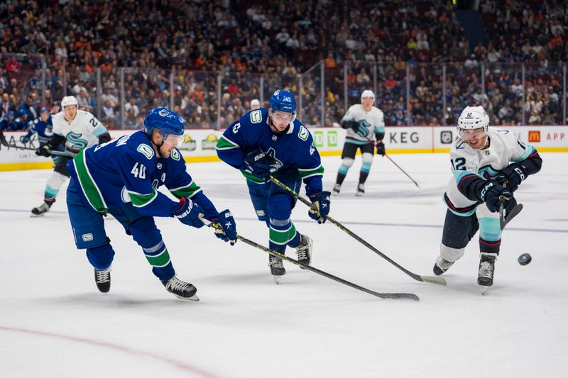 Sep 29, 2022; Vancouver, British Columbia, CAN; Vancouver Canucks forward Elias Pettersson (40) and defenseman Quinn Hughes (43) play for the puck against Seattle Kraken forward Andrew Poturalski (12) in the second period at Rogers Arena. Mandatory Credit: Bob Frid-USA TODAY Sports