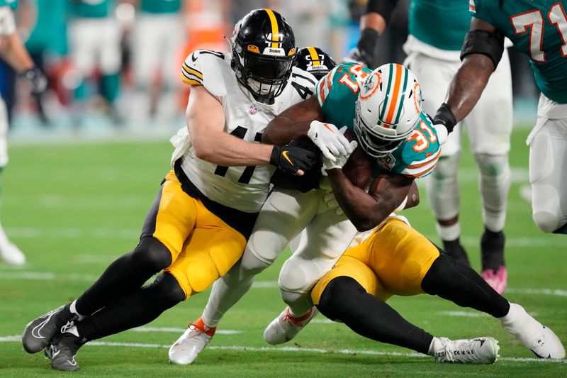 Pittsburgh Steelers linebacker Robert Spillane (41) and defensive tackle Montravius Adams (57) tackle Miami Dolphins running back Raheem Mostert (31) during the first half of an NFL football game, Sunday, Oct. 23, 2022, in Miami Gardens, Fla. (AP Photo/Rebecca Blackwell)