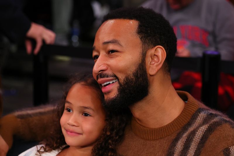 NEW YORK, NEW YORK - DECEMBER 25: American singer-songwriter and pianist John Legend and his daughter watch the game between the New York Knicks and Milwaukee Bucks at Madison Square Garden on December 25, 2023 in New York City.  NOTE TO USER: User expressly acknowledges and agrees that, by downloading and or using this photograph, User is consenting to the terms and conditions of the Getty Images License Agreement. (Photo by Rich Graessle/Getty Images)