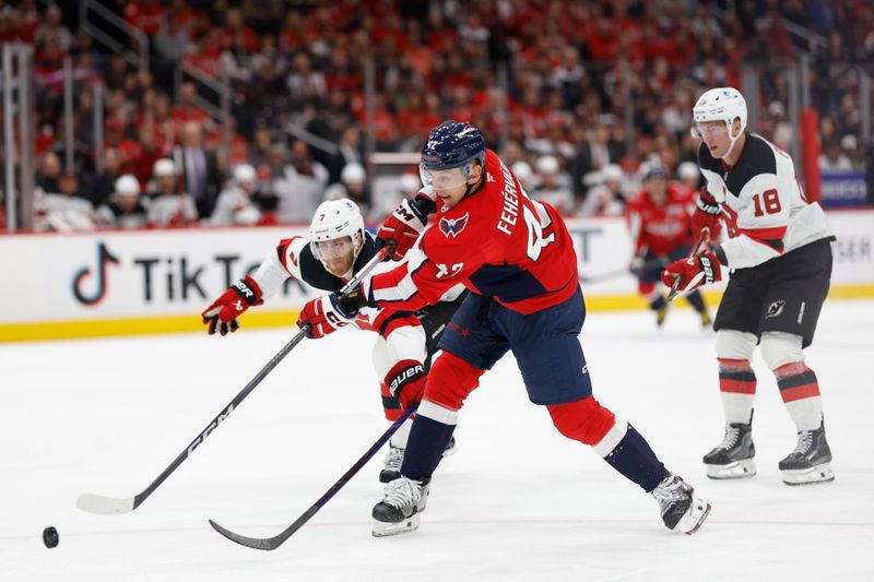 Oct 12, 2024; Washington, District of Columbia, USA; Washington Capitals defenseman Martin Fehervary (42) shoots the puck as New Jersey Devils defenseman Dougie Hamilton (7) defends in the third period at Capital One Arena. Mandatory Credit: Geoff Burke-Imagn Images