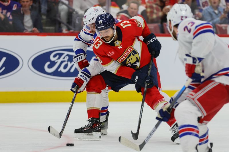 May 28, 2024; Sunrise, Florida, USA; Florida Panthers center Sam Reinhart (13) moves the puck ahead of New York Rangers defenseman Ryan Lindgren (55) during the second period in game four of the Eastern Conference Final of the 2024 Stanley Cup Playoffs at Amerant Bank Arena. Mandatory Credit: Sam Navarro-USA TODAY Sports