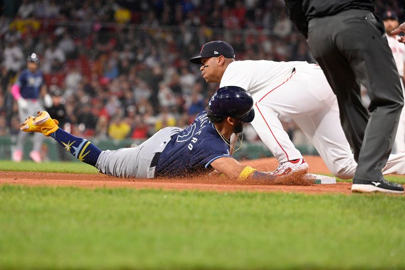 May 15, 2024; Boston, Massachusetts, USA;  Tampa Bay Rays shortstop Jose Caballero (7) slides into third base covered by Boston Red Sox third baseman Rafael Devers (11) during the sixth inning at Fenway Park. Mandatory Credit: Eric Canha-USA TODAY Sports