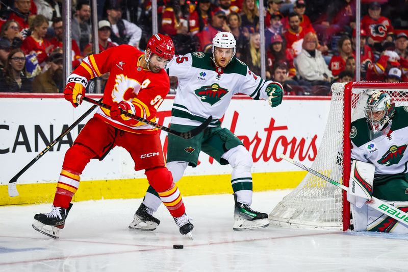 Apr 11, 2025; Calgary, Alberta, CAN; Calgary Flames center Nazem Kadri (91) controls the puck in front of Minnesota Wild goaltender Filip Gustavsson (32) during the second period at Scotiabank Saddledome. Mandatory Credit: Sergei Belski-Imagn Images