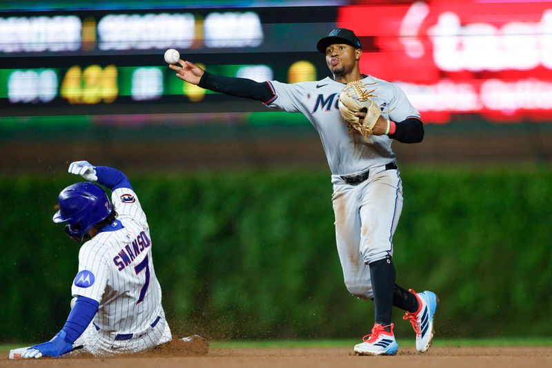 May 14, 2025; Chicago, Illinois, USA; Miami Marlins shortstop Xavier Edwards (9) throws out Chicago Cubs shortstop Dansby Swanson (7) at second base during the eight inning at Wrigley Field. Mandatory Credit: Kamil Krzaczynski-Imagn Images