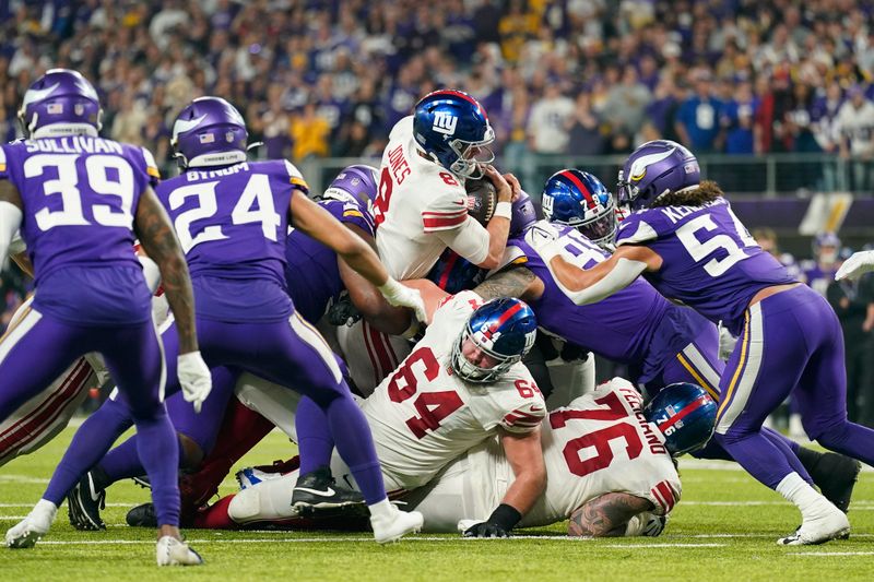 New York Giants quarterback Daniel Jones (8), middle, pushes for a first down during the second half of an NFL wild-card football game against the Minnesota Vikings, Sunday, Jan. 15, 2023, in Minneapolis. (AP Photo/Abbie Parr)