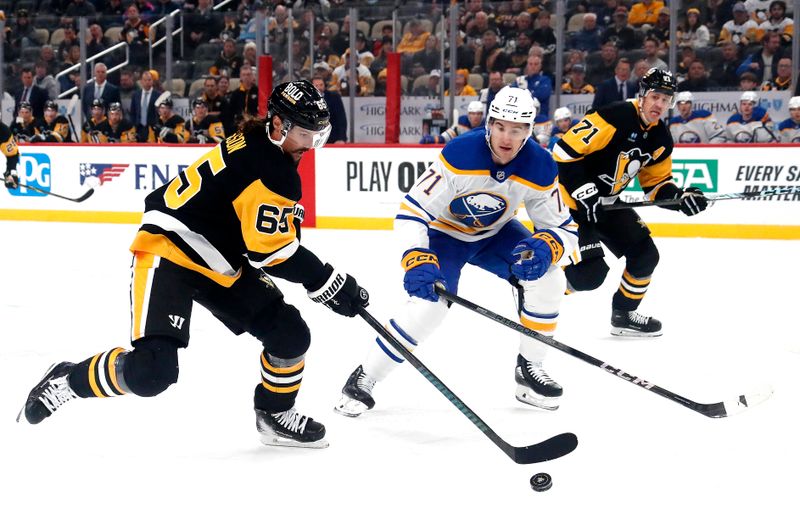 Oct 16, 2024; Pittsburgh, Pennsylvania, USA; Pittsburgh Penguins defenseman Erik Karlsson (65) moves the puck against Buffalo Sabres center Ryan McLeod (71) during the first period at PPG Paints Arena. Mandatory Credit: Charles LeClaire-Imagn Images