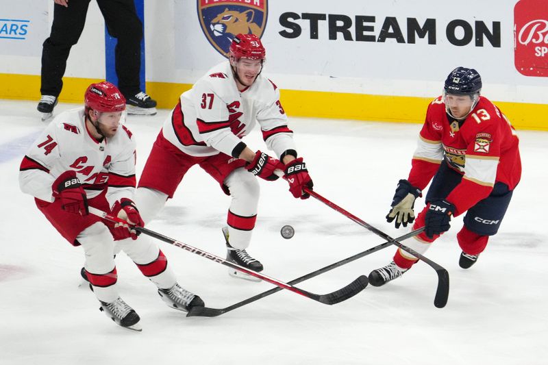 Nov 10, 2023; Sunrise, Florida, USA; Carolina Hurricanes defenseman Jaccob Slavin (74) and right wing Andrei Svechnikov (37) battle Florida Panthers center Sam Reinhart (13) for a loose puck during the third period at Amerant Bank Arena. Mandatory Credit: Jasen Vinlove-USA TODAY Sports