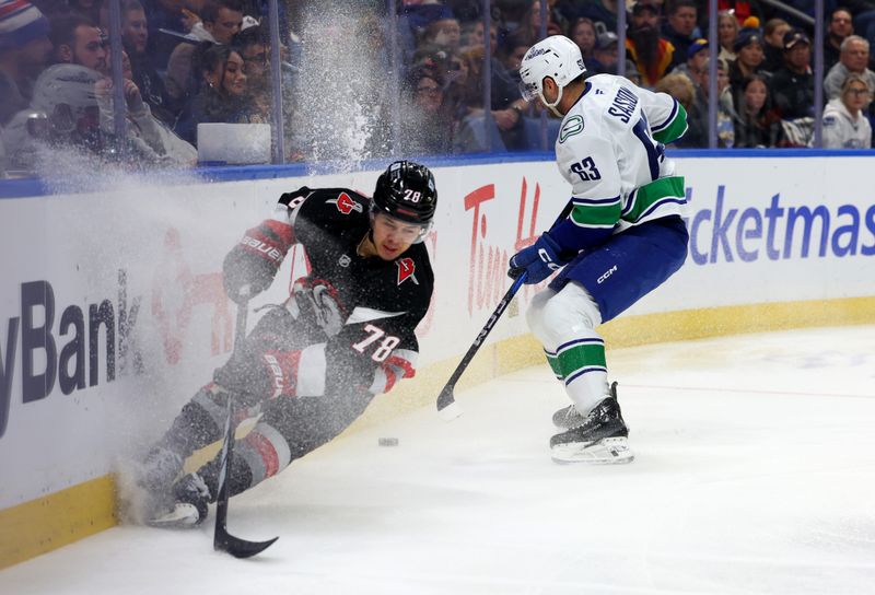 Nov 29, 2024; Buffalo, New York, USA;  Buffalo Sabres defenseman Jacob Bryson (78) and Vancouver Canucks center Max Sasson (63) go after a loose puck during the first period at KeyBank Center. Mandatory Credit: Timothy T. Ludwig-Imagn Images